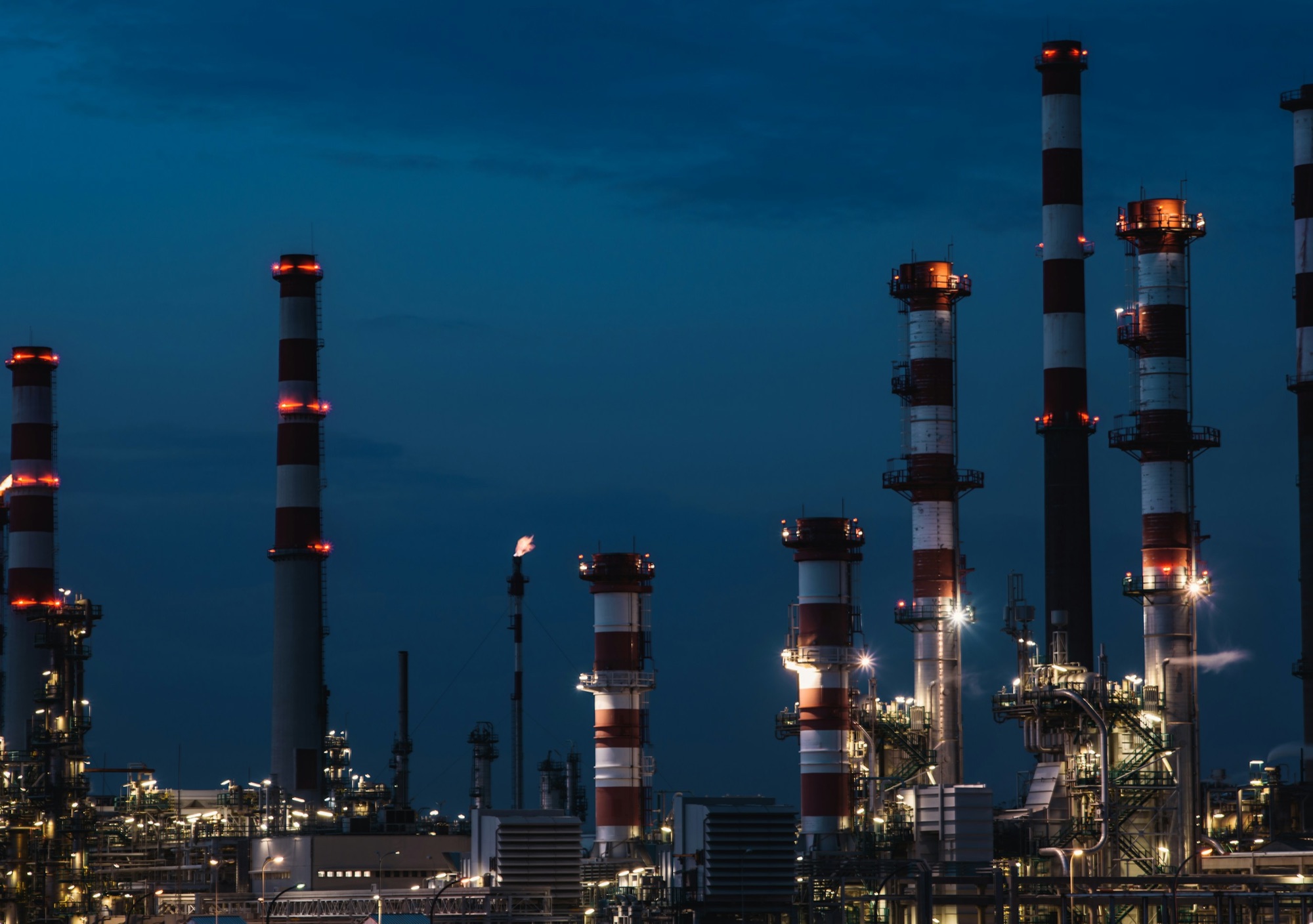 Chaminés de uma planta industrial iluminadas à noite